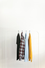 Rack with capsule clothes over white background Minimalism concept