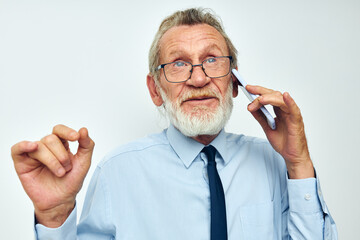 elderly man in a shirt with a tie with a phone technology light background