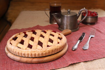Homemade Danish pie with cherry on the table among the silverware for tea drinking. 