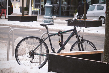 Fototapeta na wymiar Biciycle parked in winter near wooden tree box on snow