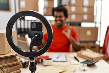 African man working at small business ecommerce doing video tutorial doing ok sign with fingers, smiling friendly gesturing excellent symbol