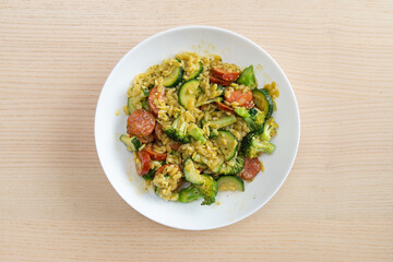 A plate of chorizo risoni pasta with broccoli and zucchini.