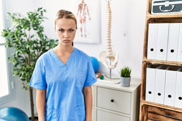 Young caucasian woman working at pain recovery clinic skeptic and nervous, frowning upset because of problem. negative person.