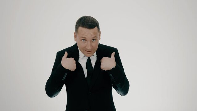 Young male businessman 30 years old, medium plan in a black suit. Pointing at himself with two fingers. Questioningly asks and refuses. He waved his arms expressively.