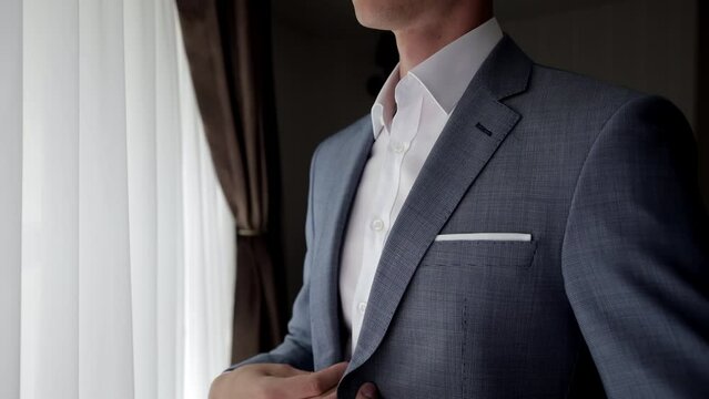 Close up view of man adjusts his suit. Business man put suit on during morning routine at home, preparing to go to work