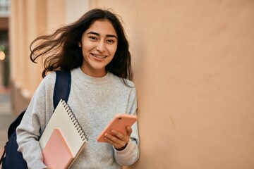Young middle east student girl smiling happy using smartphone at the city.