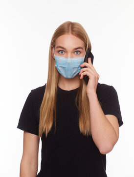 European Girl in a mask uses a telephone. Conceptual photo on the theme of the epidemic.