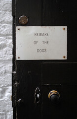 Metal Sign on Old Black Painted Door 'Beware of The Dogs' 
