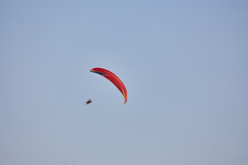 Paragliding in the sky. Paraglider flying in bright sunny day. Beautiful paraglider in flight on a turquise background.