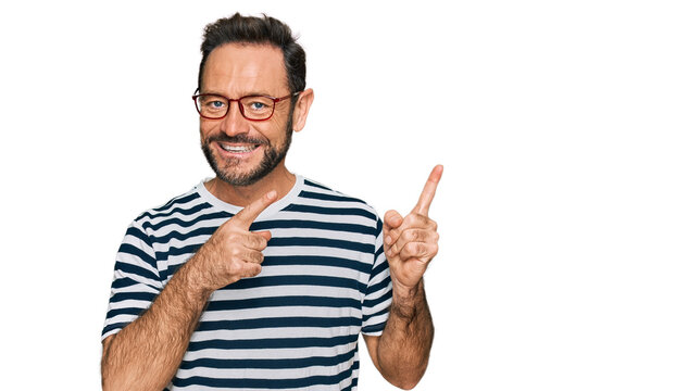 Middle age man wearing casual clothes and glasses smiling and looking at the camera pointing with two hands and fingers to the side.