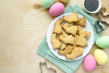 Easter cookies with poppy seeds in the shape of bunnies on wooden background, space for text