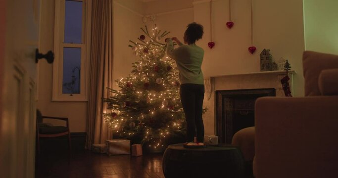 Woman Home Alone Decorating Christmas Tree and Dancing