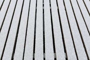 Snow-covered modern wooden pier (jetty, boardwalk) over the frozen river. Ice, frost, snow...