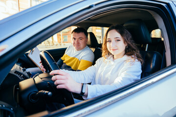 Close up hands turn steering wheel. Female student at driving courses hold the wheel and male instructor helps her to drive. Driving lessons concept.