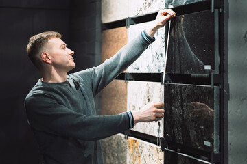 a man in a store near a stand with samples of beautiful granite and marble measures samples with a tape measure