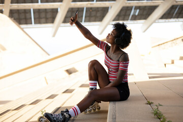 Beautiful African woman with roller skates. Urban sexy girl taking selfie photo