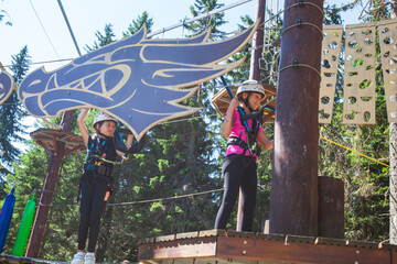 Children using safety equipment at climbing adventure amusement park. Child outdoor sports activity.