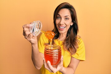 Young latin woman holding honey celebrating crazy and amazed for success with open eyes screaming...