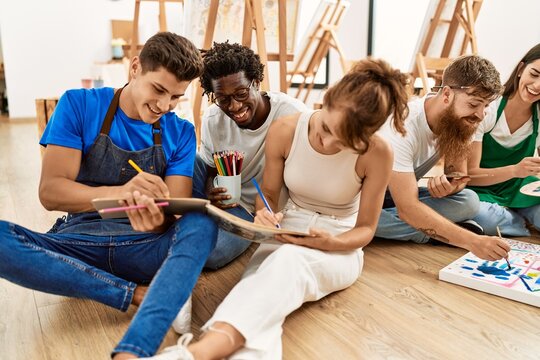 Group of people smiling happy drawing sitting on the floor at art studio.