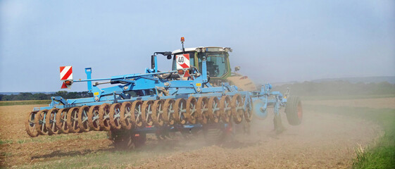 On a field in Wennerode am Harz in the state of Lower Saxony, a tractor is cultivating heavy Harz...