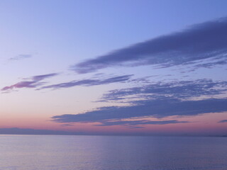 Beautiful sunset over the sea. Small waves, unusual clouds, bright pink-blue sky.