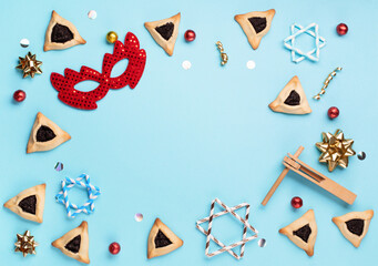 Fototapeta na wymiar Purim celebration jewish carnival holiday concept. Tasty hamantaschen cookies, red carnival mask, noisemaker, sweet candies and party decor on blue background. Top view, flat lay, copy space.