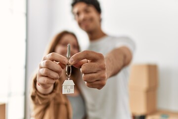 Young couple smiling happy holding key of new home.