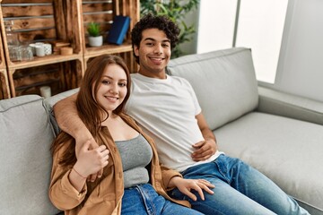 Young couple smiling happy and hugging sitting on the sofa at home.