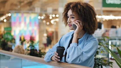 Successful african american business woman talking mobile phone answering call calling service online shopping booking making order with smartphone drinking tea coffee in mall company free wifi tech