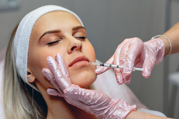 Cosmetic procedures for face rejuvenation. Lip augmentation Botox injections. Master beautician...