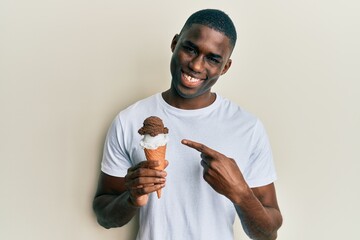 Young african american man holding ice cream smiling happy pointing with hand and finger