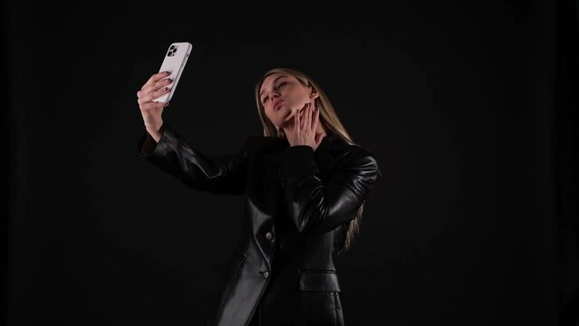 blonde woman in black jacket taking a selfie