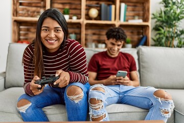 Woman playing video game and man using smartphone at home.