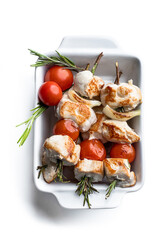 Grilled chicken kebab and vegetables on rosemary stick in a white plate isolated on white