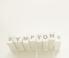Symptoms word from wooden blocks with letters, viral diseases prevention and healing concept, blue...