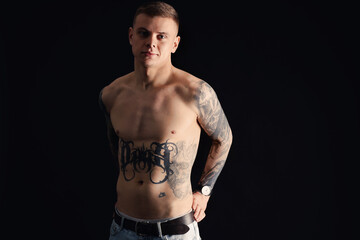 Fototapeta premium Shirtless young man with tattoos on black background