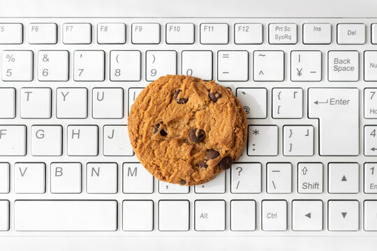 ノートパソコンのキーボードとクッキー。デジタルデバイスのCookieイメージ