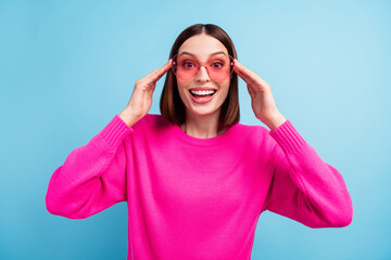 Photo of impressed funky young woman dressed pink sweater arms heart glasses smiling isolated blue color background