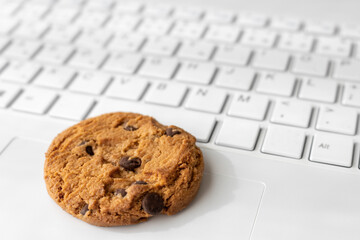 ノートパソコンのキーボードとクッキー。デジタルデバイスのCookieイメージ