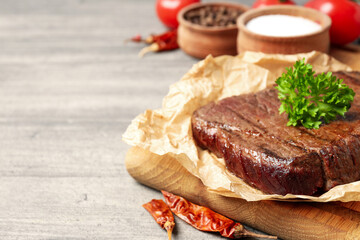 Concept of tasty food with beef steak on gray wooden background