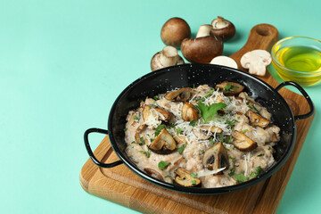 Concept of tasty food with risotto with mushrooms on mint background