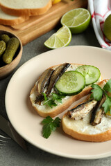 Concept of tasty snack with sandwiches with sprats on gray textured background