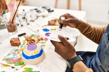 African american artist man mixing color on palette at art studio.