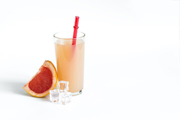 Natural grapefruit juice and a slice of grapefruit on a white background is a place for text. Grapefruit juice in a glass glass with a bright red tube natural light.