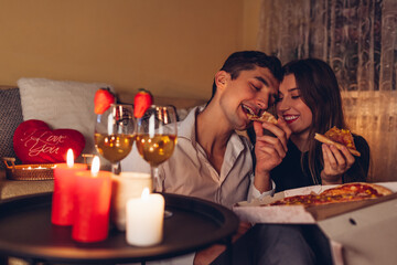 Valentines Day couple in love eating pizza drinking wine with strawberries having romantic dinner celebrating at home