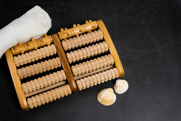 Foot roller massager on a black ground. Towel and shells. Home Spa.