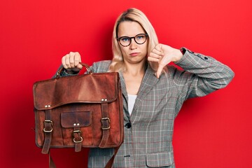 Beautiful caucasian blonde business woman wearing leather bag with angry face, negative sign...
