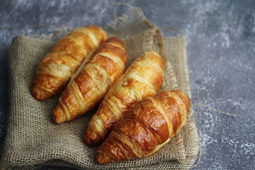 Croissant bread stacked on the table with wooden plates and sackcloth.