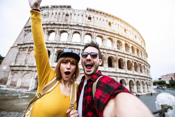 Young couple at Colosseum, Rome - Happy tourists visiting Italian famous landmark - Friends enjoying vacation in Italy - Holidays and happy lifestyle concept