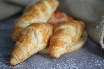 Croissant bread stacked on the table with wooden plates and sackcloth.
